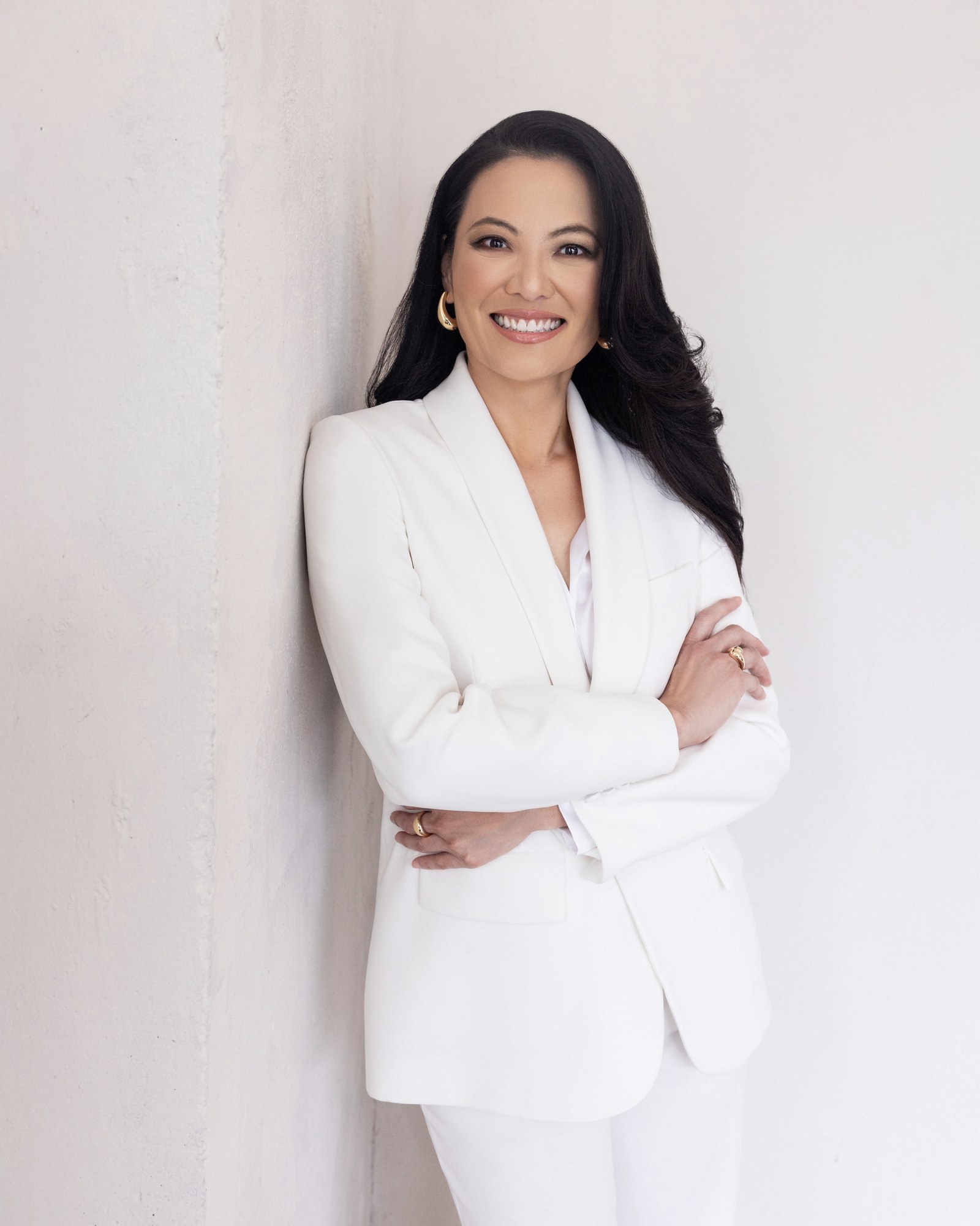 Dr. Justine C. Lee in a white blazer with arms crossed, professional studio portrait